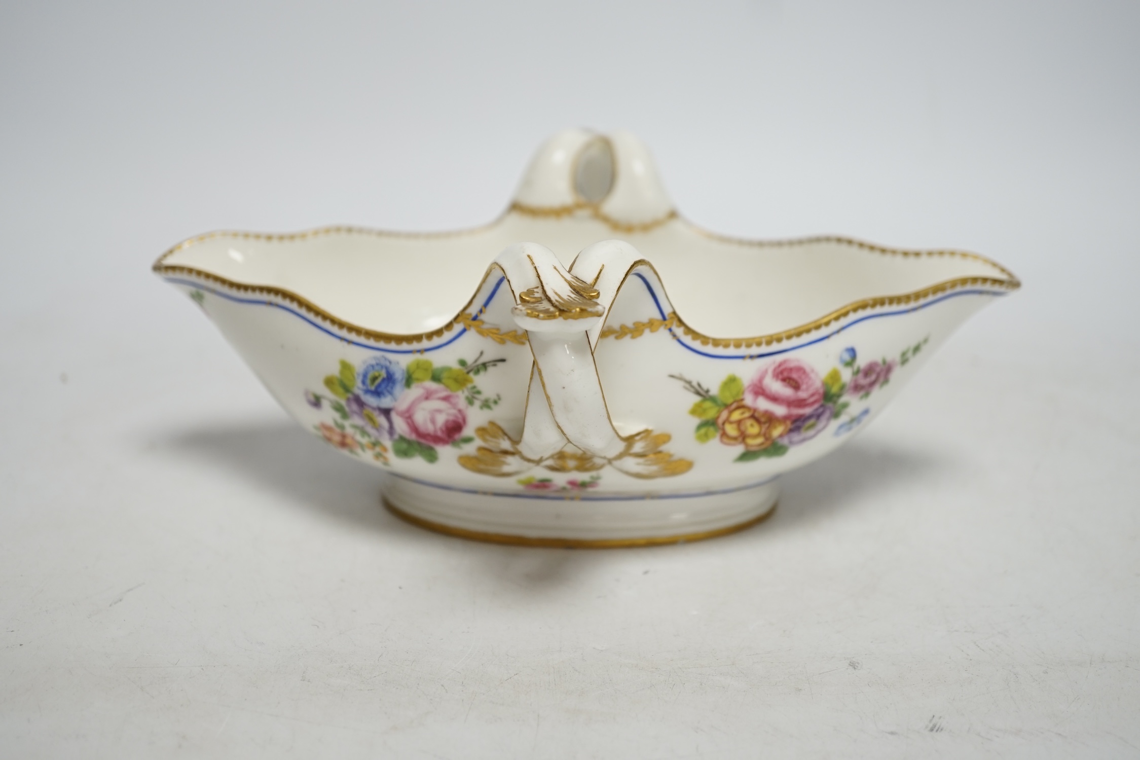 An 18th century Sevres sauceboat, probably later enamelled with flowers, 23.5cm wide